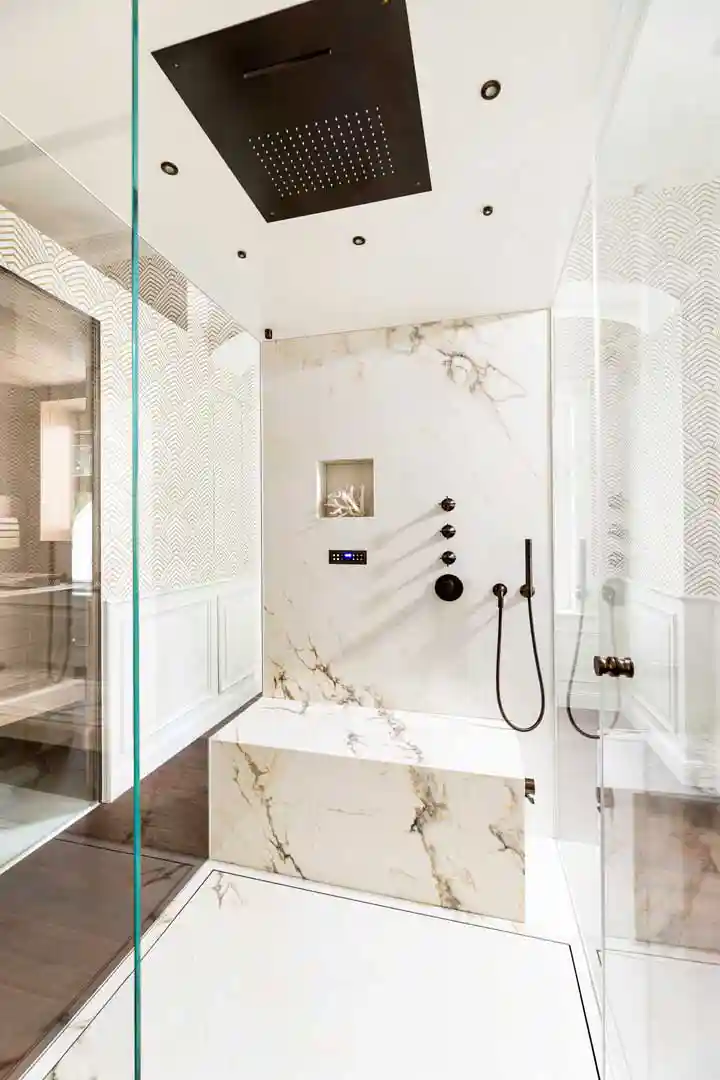 Dampfdusche in marmorooptik mit aus hellen Fliesen in Marmor Struktur und schwarzen Armaturen